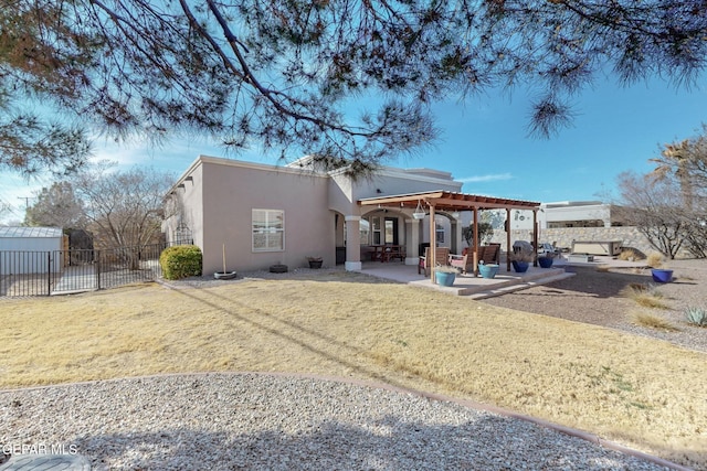 rear view of house featuring a lawn, a patio area, fence, and stucco siding