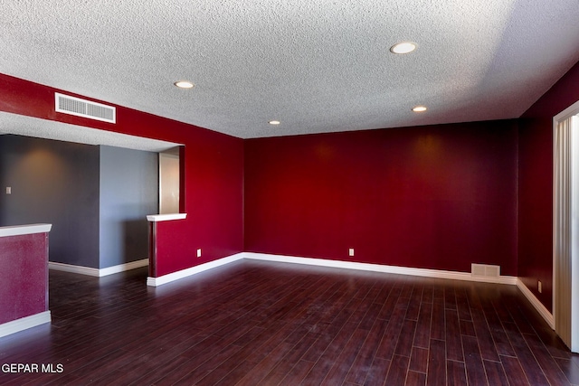 spare room with dark hardwood / wood-style floors and a textured ceiling