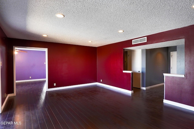 empty room with a textured ceiling and dark hardwood / wood-style flooring