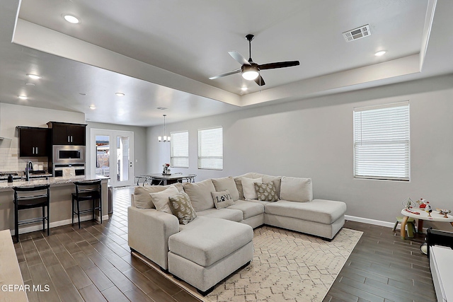 living room featuring wood finish floors, a raised ceiling, visible vents, and baseboards