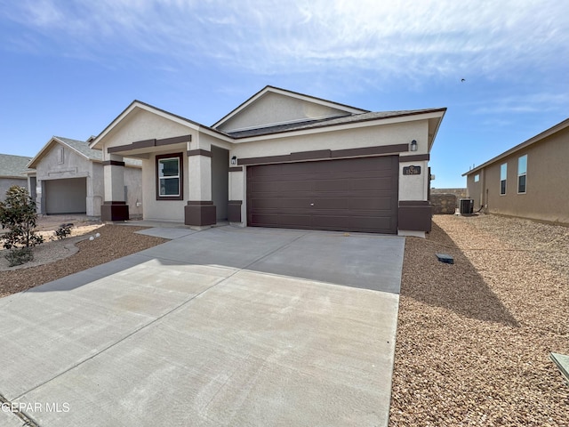 ranch-style house featuring concrete driveway, central AC, an attached garage, and stucco siding