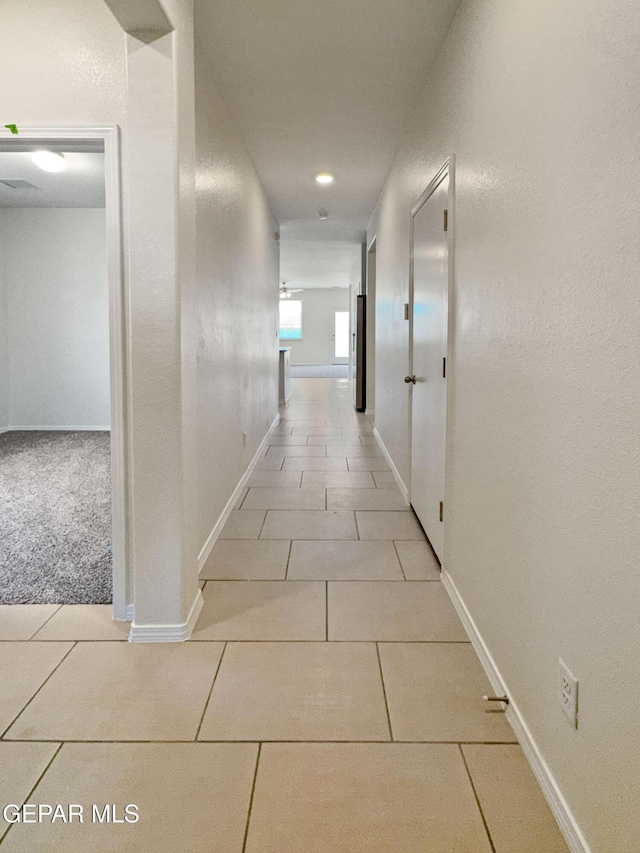 corridor featuring light tile patterned floors and baseboards