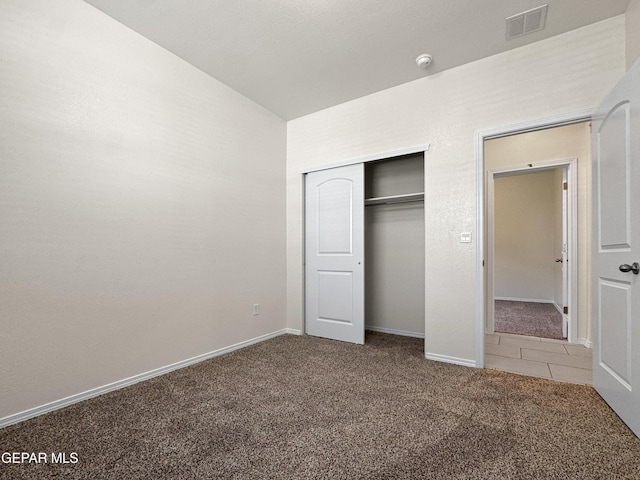 unfurnished bedroom featuring baseboards, visible vents, tile patterned flooring, carpet flooring, and a closet