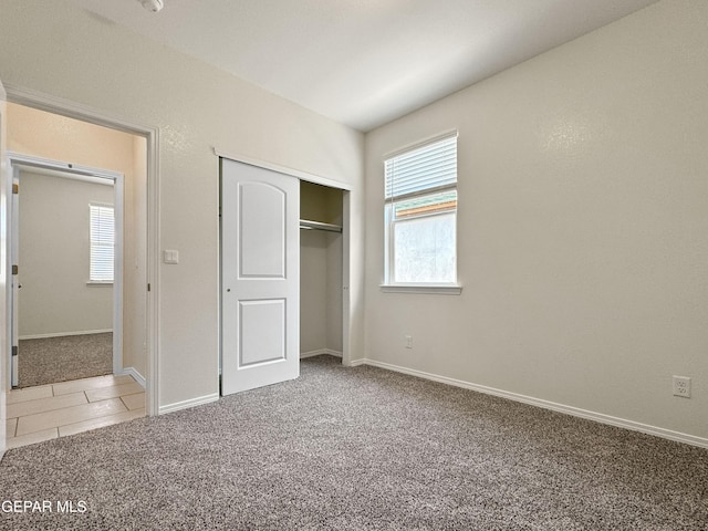 unfurnished bedroom with a closet, tile patterned flooring, carpet flooring, and baseboards