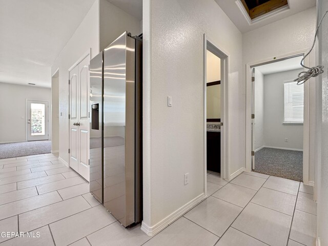 hallway featuring light tile patterned floors, light colored carpet, and baseboards