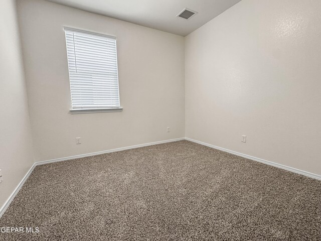 empty room featuring carpet floors, visible vents, and baseboards