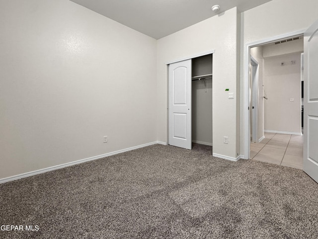 unfurnished bedroom featuring a closet, light carpet, visible vents, and baseboards