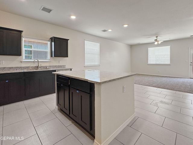 kitchen featuring a kitchen island, visible vents, a sink, and dark cabinetry