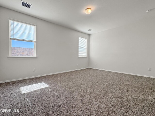 empty room with baseboards, visible vents, and carpet flooring