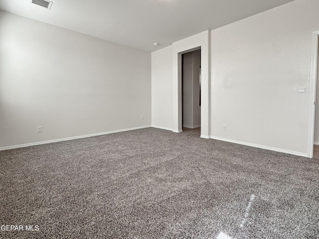 empty room featuring carpet floors, visible vents, and baseboards