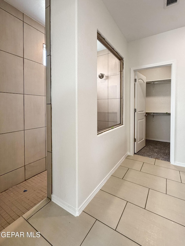 hallway with visible vents, baseboards, and tile patterned floors