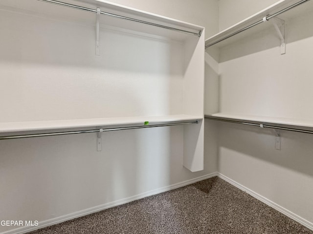 walk in closet featuring dark colored carpet