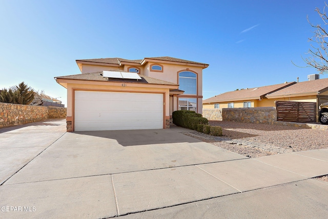 view of front of property featuring a garage, central AC unit, concrete driveway, fence, and stucco siding