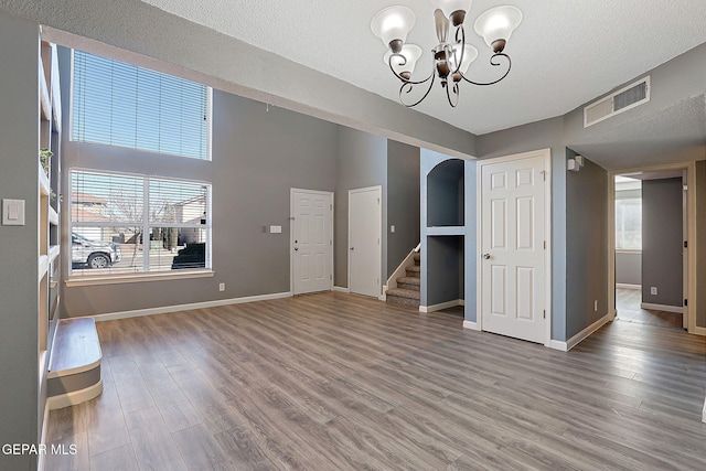 unfurnished living room with stairway, baseboards, visible vents, and wood finished floors