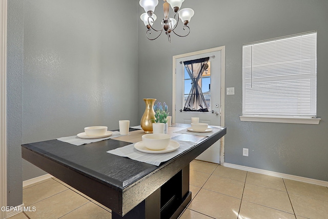 dining area featuring light tile patterned floors, baseboards, and a notable chandelier