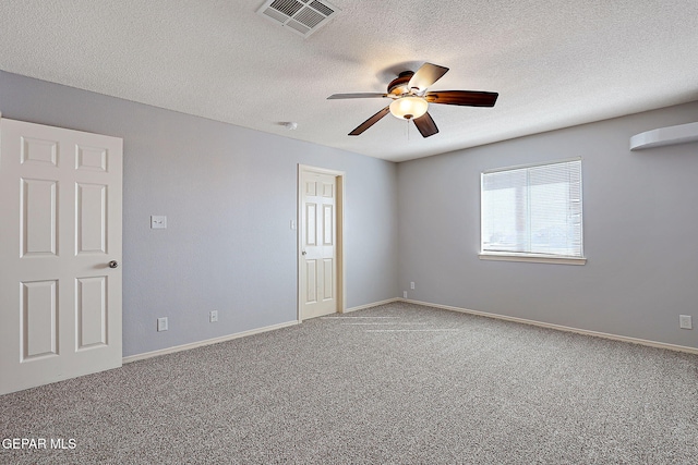 carpeted spare room featuring a textured ceiling, ceiling fan, visible vents, and baseboards