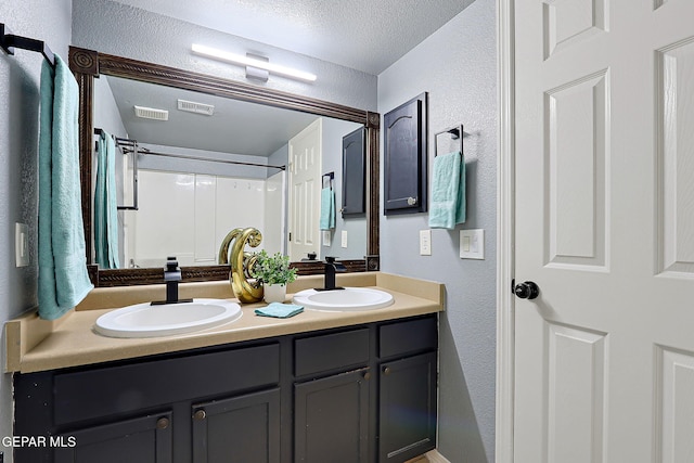 full bath with a textured ceiling, visible vents, a sink, and a textured wall