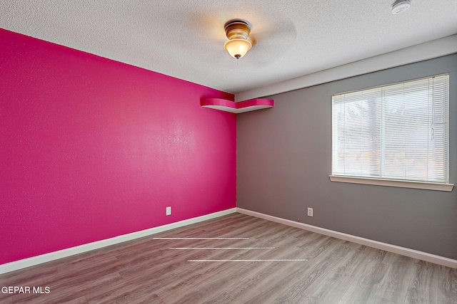 spare room featuring wood finished floors, a wealth of natural light, and baseboards