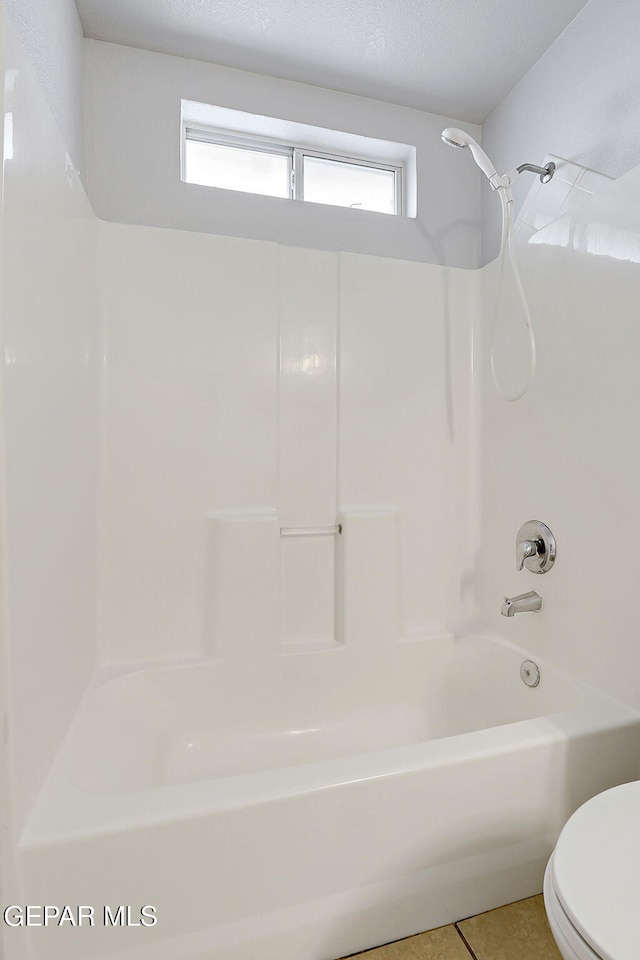 bathroom with toilet, shower / tub combination, a textured ceiling, and tile patterned floors