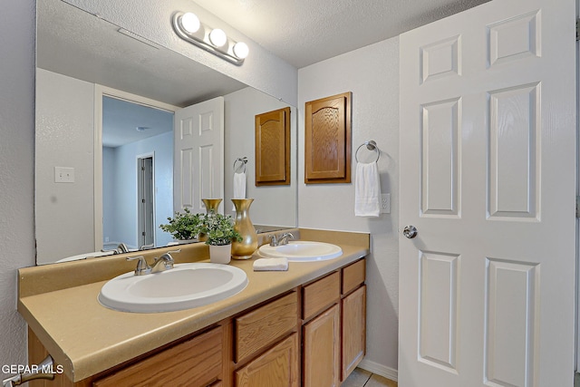 bathroom featuring double vanity, a textured ceiling, and a sink