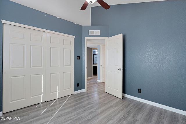 unfurnished bedroom with light wood finished floors, baseboards, visible vents, a ceiling fan, and a closet