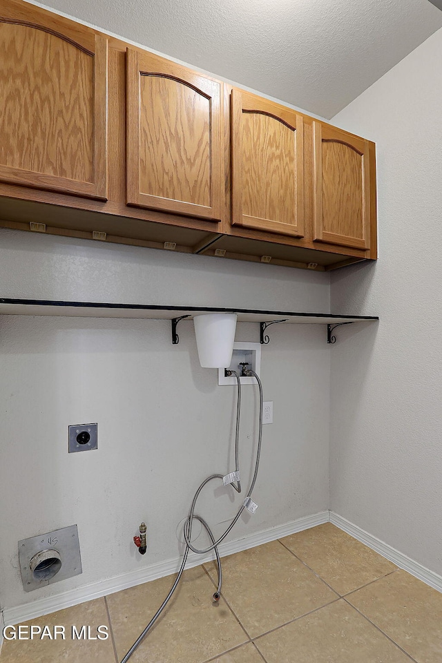 laundry area featuring gas dryer hookup, light tile patterned flooring, washer hookup, baseboards, and cabinet space