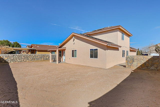 rear view of house featuring fence and stucco siding