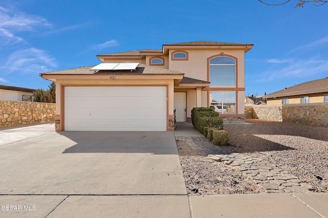 view of front facade featuring stucco siding, solar panels, concrete driveway, fence, and a garage