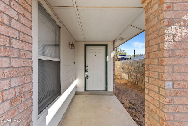 doorway to property featuring brick siding and fence