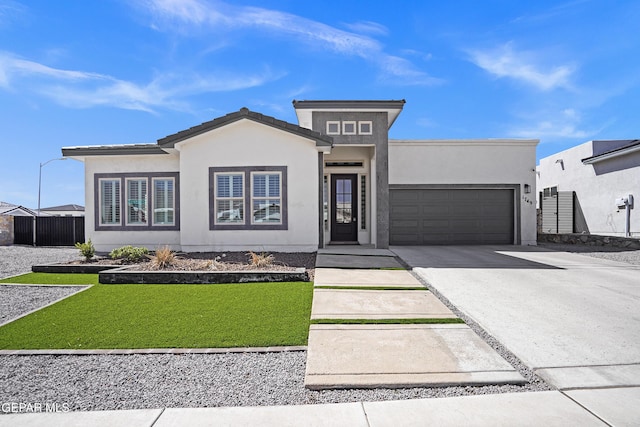 view of front facade with an attached garage, fence, concrete driveway, and stucco siding