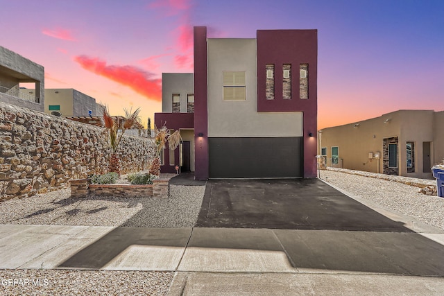 view of front of home with a garage, aphalt driveway, and stucco siding