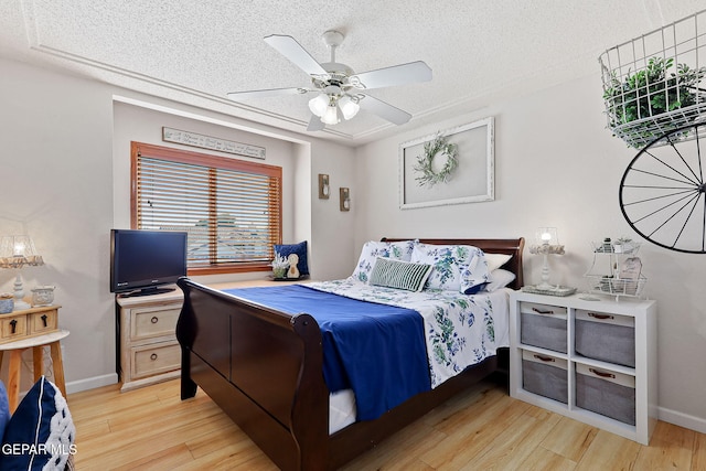 bedroom featuring a textured ceiling, ceiling fan, light wood-type flooring, and baseboards