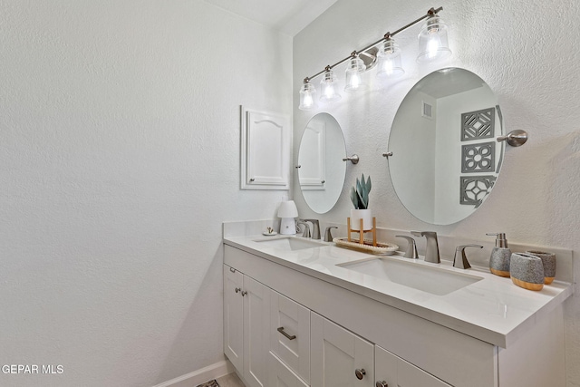 bathroom featuring a textured wall, a sink, and double vanity