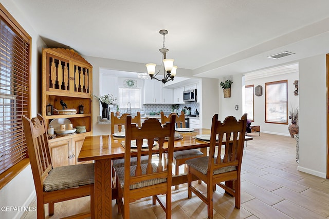 dining space featuring baseboards, visible vents, and a chandelier