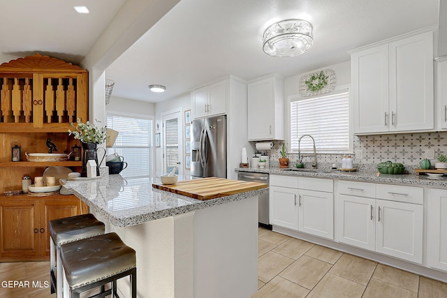 kitchen featuring stainless steel appliances, white cabinets, and light stone counters