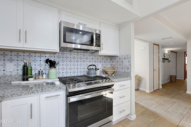 kitchen featuring visible vents, stainless steel appliances, light stone counters, and white cabinetry