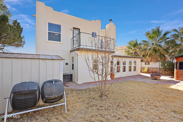 rear view of house with a fire pit, a lawn, a balcony, metal roof, and a standing seam roof