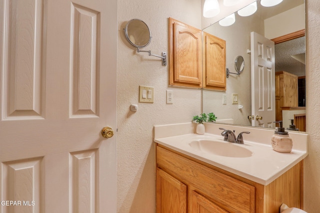 bathroom with a textured wall and vanity