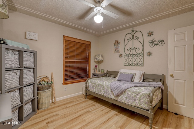 bedroom featuring light wood-style floors, ceiling fan, a textured ceiling, and baseboards