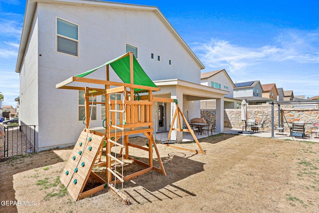 view of jungle gym with a patio area and fence