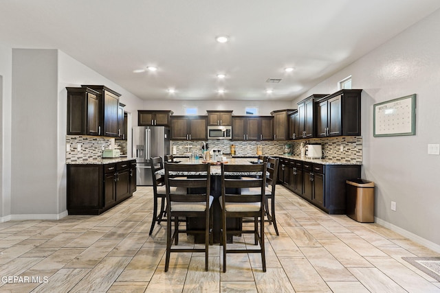 kitchen with dark brown cabinets, tasteful backsplash, visible vents, and stainless steel appliances