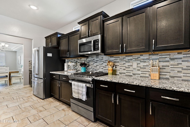 kitchen featuring stainless steel appliances, decorative backsplash, and light stone counters