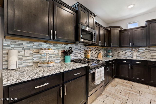 kitchen with light stone countertops, stainless steel appliances, and tasteful backsplash