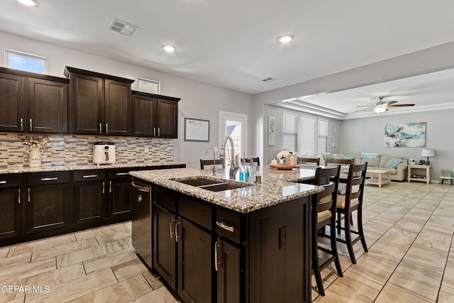 kitchen with a sink, open floor plan, visible vents, a kitchen bar, and decorative backsplash