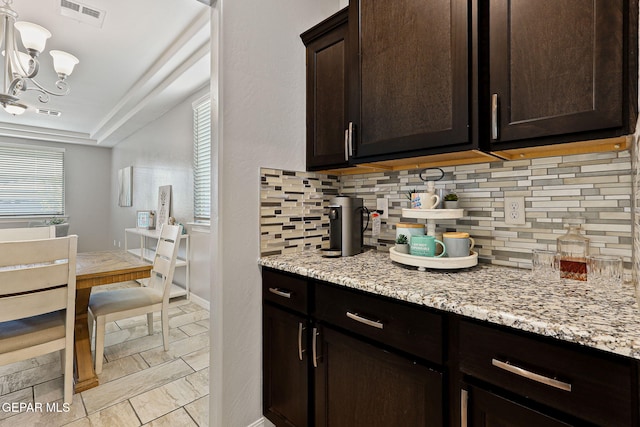 kitchen featuring a notable chandelier, dark brown cabinets, visible vents, and decorative backsplash