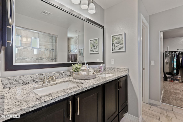 bathroom featuring baseboards, a sink, visible vents, and double vanity