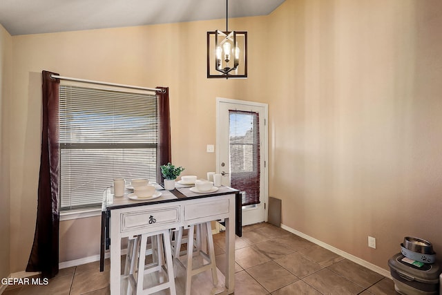 dining area with light tile patterned floors, baseboards, and a notable chandelier