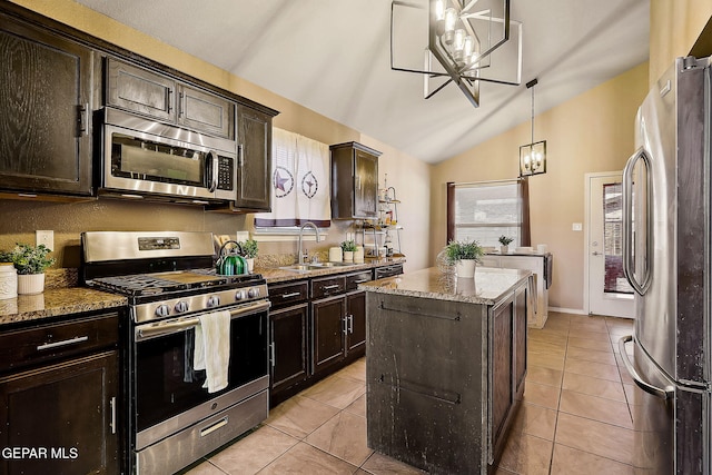 kitchen with stone countertops, stainless steel appliances, a sink, a center island, and decorative light fixtures