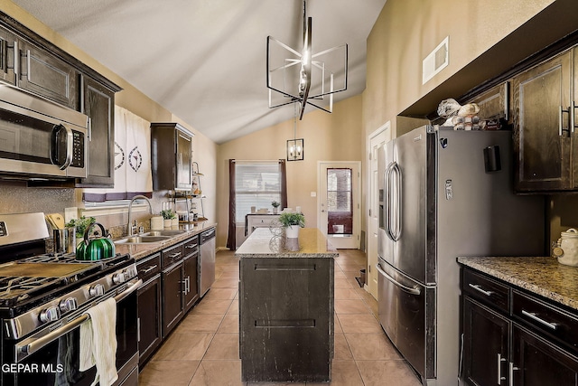 kitchen featuring light stone counters, a kitchen island, appliances with stainless steel finishes, an inviting chandelier, and pendant lighting