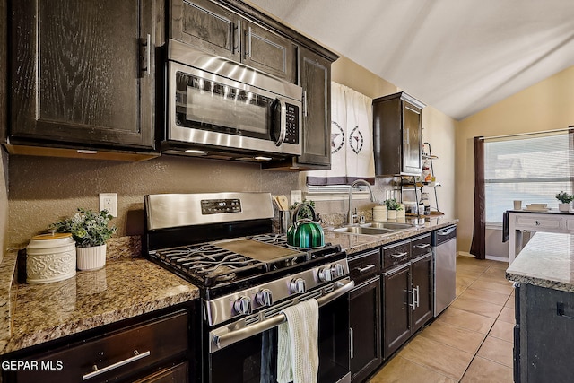 kitchen with light stone counters, appliances with stainless steel finishes, light tile patterned flooring, a sink, and dark brown cabinetry